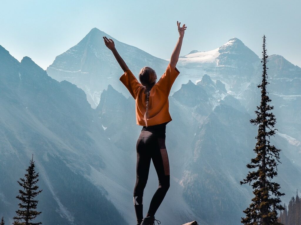 Jeune fille de dos fasse à une montagne dans une attitude triomphante.